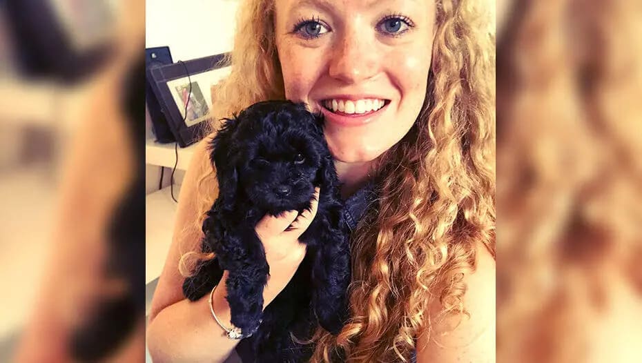 Дівчина тримає на руках чорне цуценя